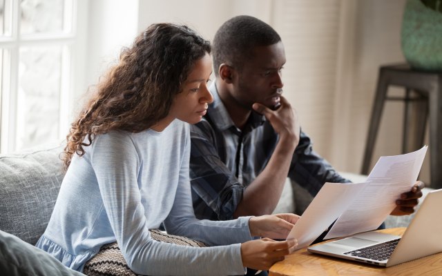 A man and woman looking at documents on a sofa